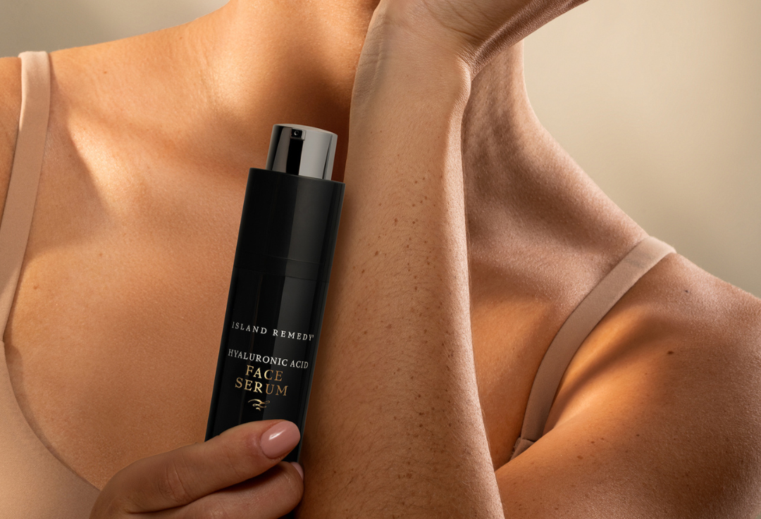 Aruba Aloe Hyaluronic Acid Serum Island Remedy Person holding a black skincare serum bottle with visible branding.